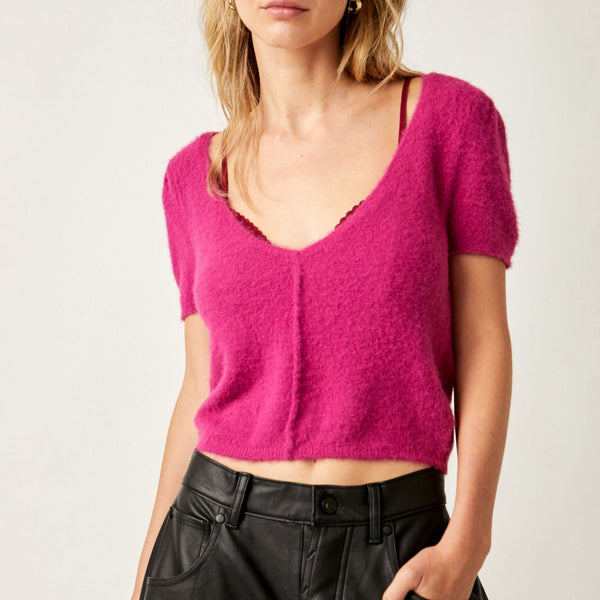 front view of model wearing keep me warm crop top in fuchsia. shows the raised seams. also the low scoop neckline, the short sleeves, the cropped length of the top and the soft texture.