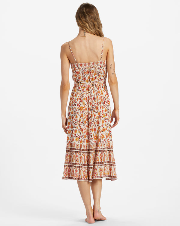 Back view of model wearing dress. Shows the spaghetti straps. Also shows the removable waist tie, the midi length, the bottom tiered ruffles and the floral print. 