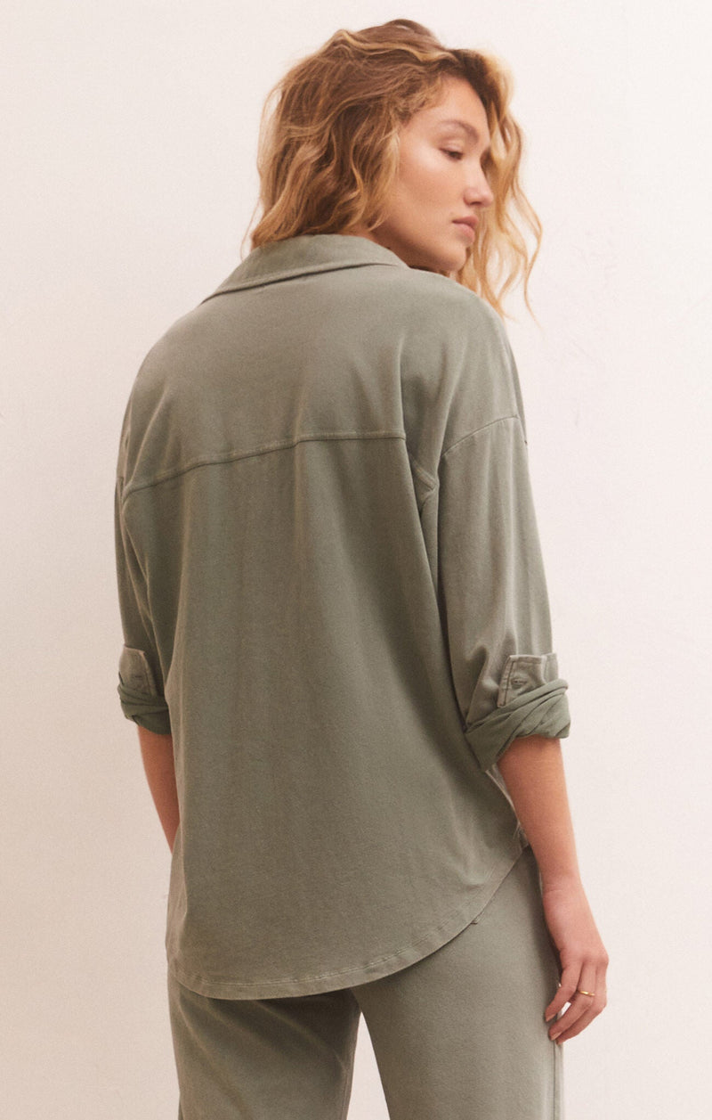 back view of model in shirt. shows the curved hem, long sleeves and horizontal seam running across the back.
