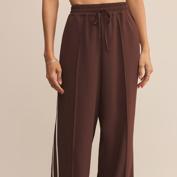 Brown wide-leg pants worn by a person on a beige background