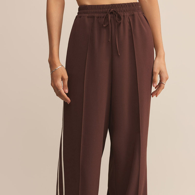 Brown wide-leg pants worn by a person on a beige background