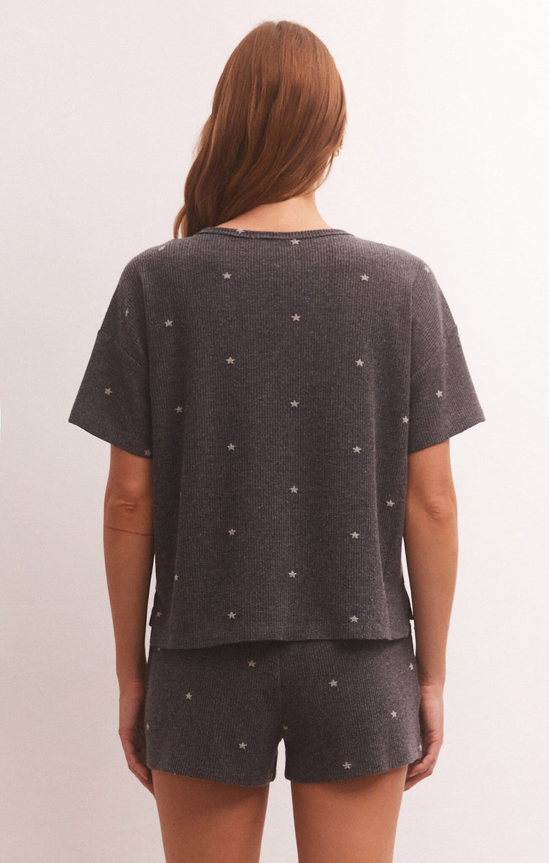 back view of model in shirt. shows relaxed fit, dropped shoulders, short sleeves and mini star print.