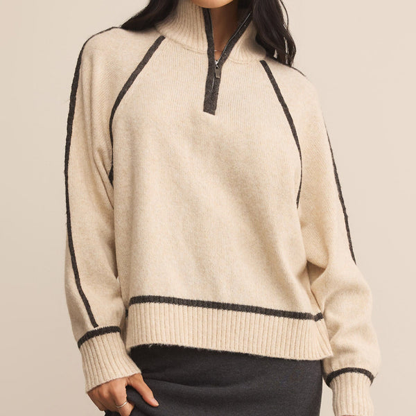 Woman wearing a beige sweater with black accents on a beige background