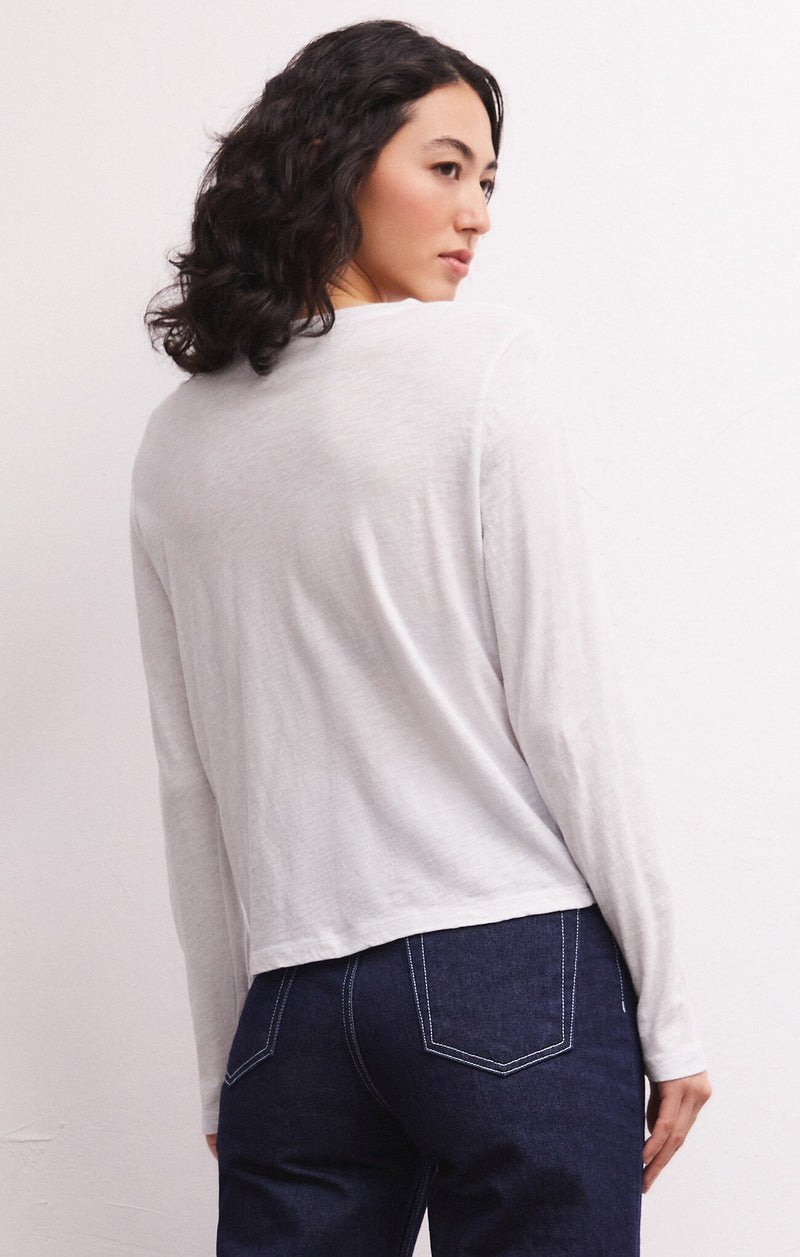 Back view of model wearing the long sleeve tee. Shows the ribbing on the neckline. Also shows the slim fit, the long sleeves in this beautiful white color.