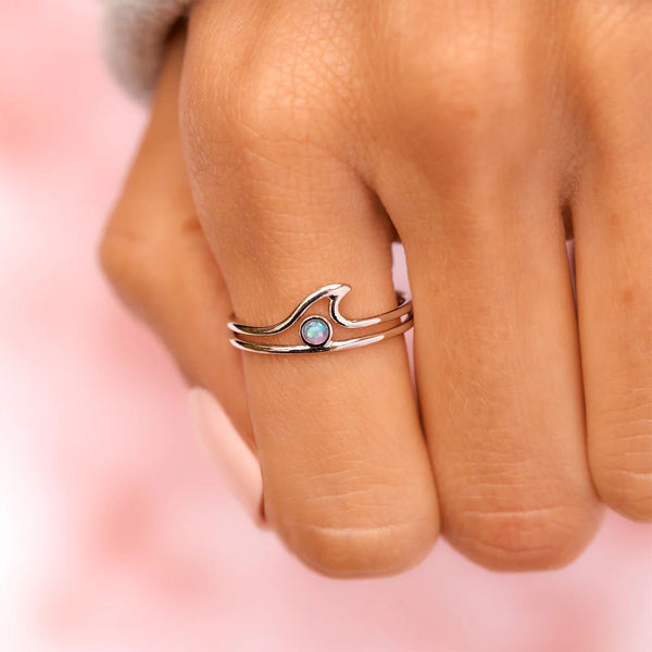 shows model wearing the silver ring with a cutout wave design and an opal stone in the center.