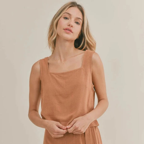front view of model in top. shows a square neckline, thick straps and cropped design. is a boxier fit.