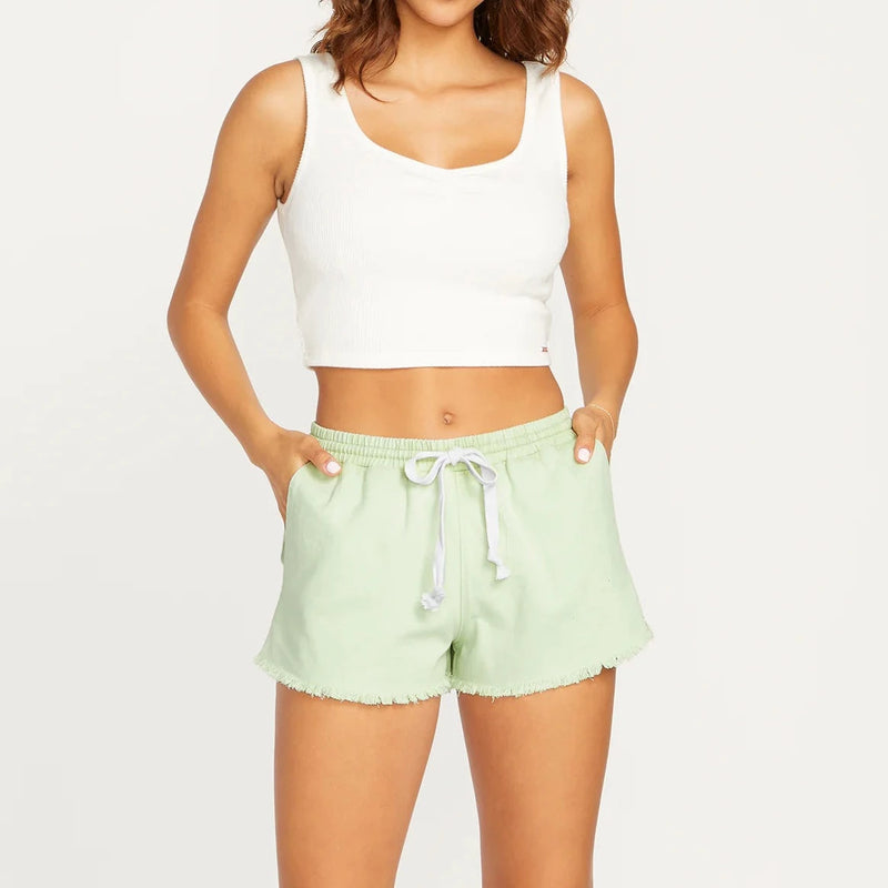 shows front view of model in the shorts. they fall just below the belly button, feature an elastic waistband with a tie drawstring and a raw hemline.