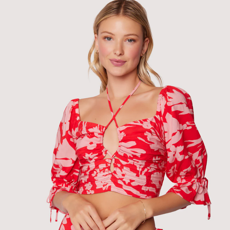 Front view of top. Features keyhole detail, halter neckline and puff sleeves with tie detail.
