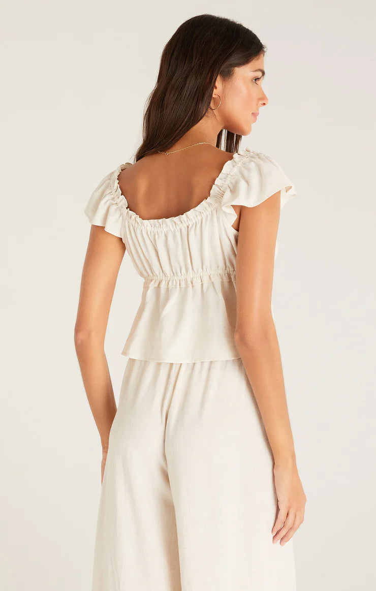 shows back view of blouse featuring a scoop back with lettuce hem, flutter sleeves, and empire tiered bodice with lettuce detail. 