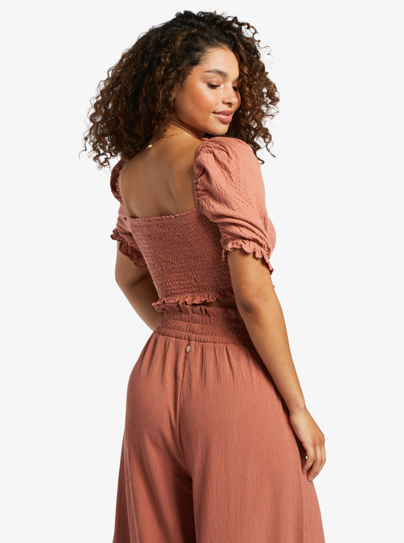 back view of model in the redwood color crop top. shows the smocked square back and puff sleeves.