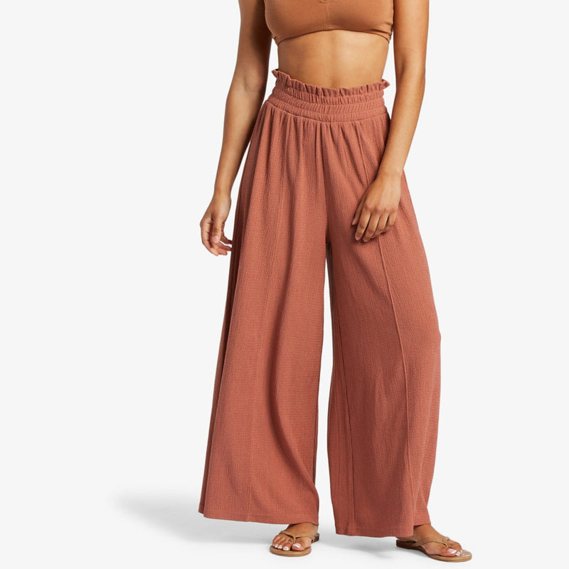 front view of model in the cedar wood pants. shows the high waisted smocked elastic waistband and wide legs.