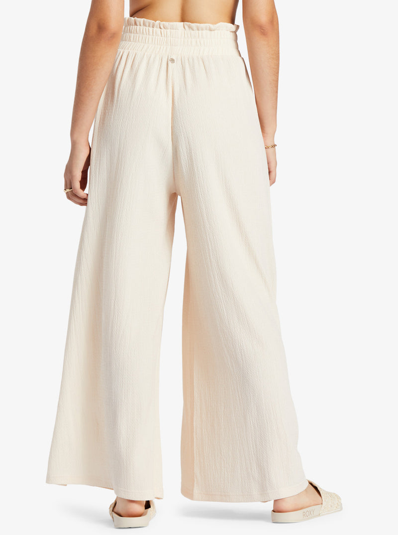 back view of model in the ivory (tapioca) pants. shows the smocked elastic waistband and wide leg. hits model at the ankle.